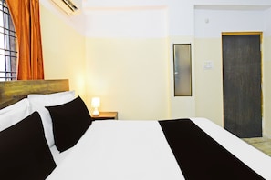 A hotel room with a bed, a nightstand with a lamp, a window with curtains, and a door. - Hotel O Suncity formerly Fort Inn (Hyderabad)