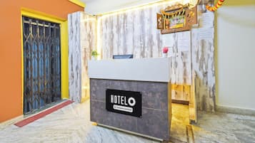 Una reception hotel con un bancone in marmo, una ventola a soffitto e una insegna a parete.