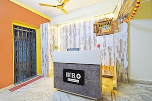 Un comptoir de réception d’hôtel avec un revêtement en marbre, un ventilateur de plafond et un panneau fixé au mur.