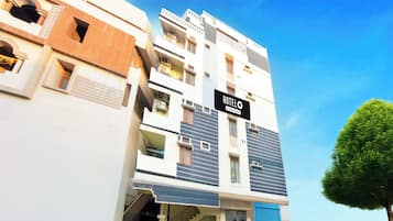 Un hotel a più piani con un cartello che indica 'HOTEL' e una scala che conduce all'ingresso.