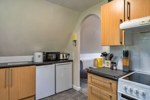 Cozinha compacta com geladeira, micro-ondas, torradeira e fogão.