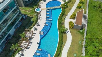 Vista aérea de um resort com uma grande piscina, áreas de estar e um jardim paisagístico.