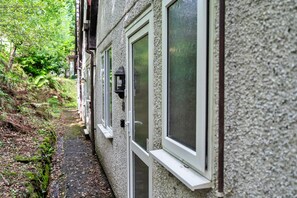 A narrow pathway leading to a building with multiple windows and a door. - Daisy Valley Lodge (Callington)