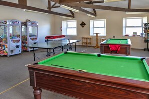 A pool table, two claw machines, and a billiards table in a room with wooden beams and large windows. - Daisy Valley Lodge (Callington)
