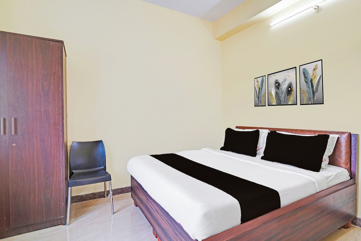 A bedroom with a bed, a wardrobe, a chair, and three wall-mounted paintings.