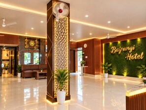 Um hall de hotel moderno com balcão de recepção, área de estar e parede decorativa com o nome do hotel.