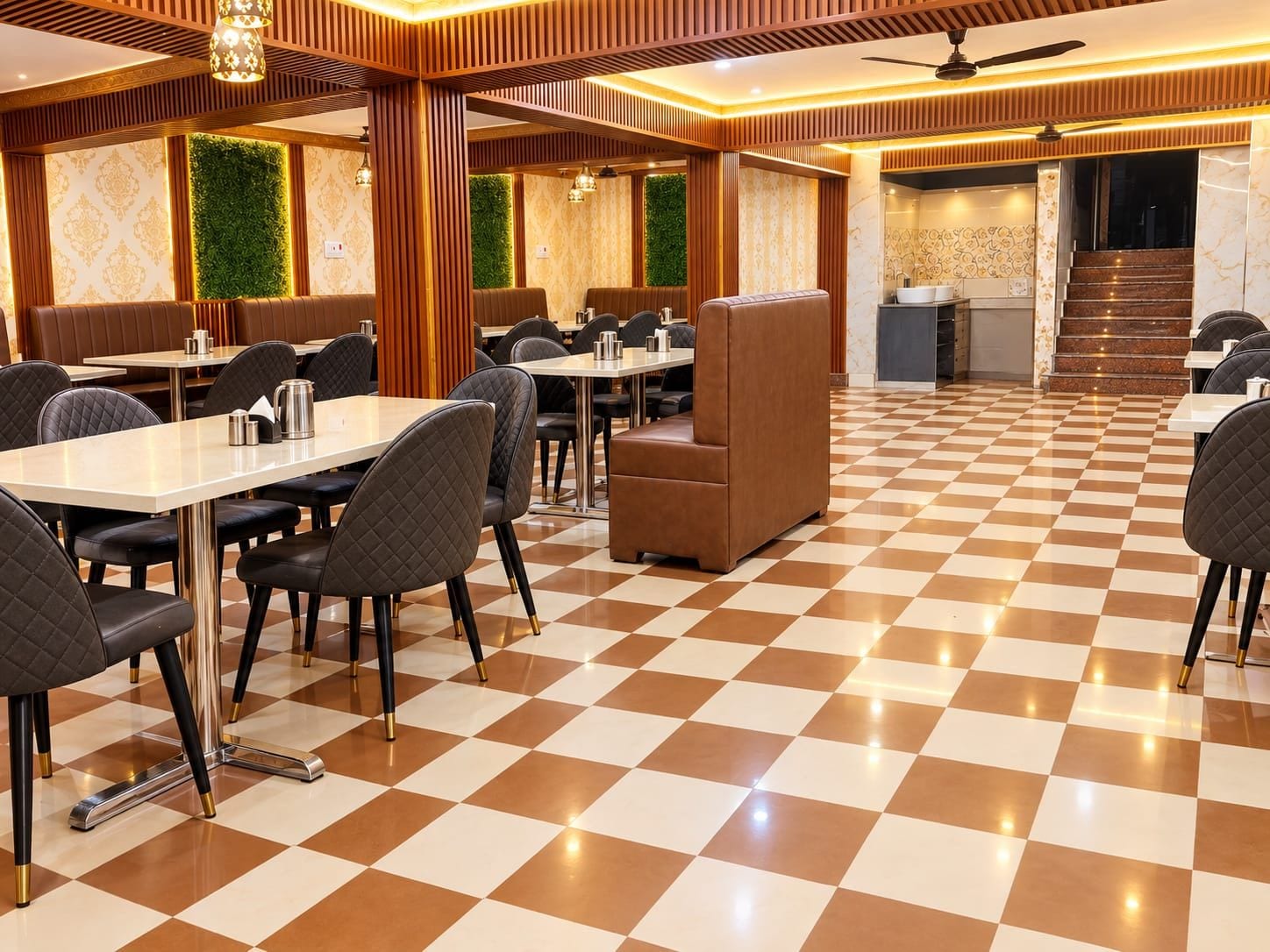 Uma área de refeições de hotel com piso xadrez, mesas, cadeiras e escada que leva ao andar superior.