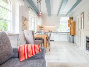 A modern kitchen with a dining area, a fireplace, and a view of the outdoors. - Holiday Apartment With 2 Bedrooms (Sylt)