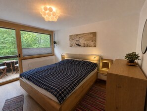 A bedroom with a bed, bedside tables, a window, and a painting on the wall. - Bergzeit - One Bedroom Apartment in Kirchberg (Kirchberg in Tirol)
