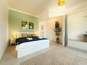 A modern bedroom with a bed, bedside tables, artwork, a potted plant, and a sliding door. - The Spacious next to University Square View and Old Town (Bucharest)
