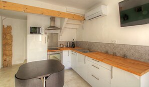 Una cocina funcional con encimera de madera, armarios blancos, horno integrado y microondas.