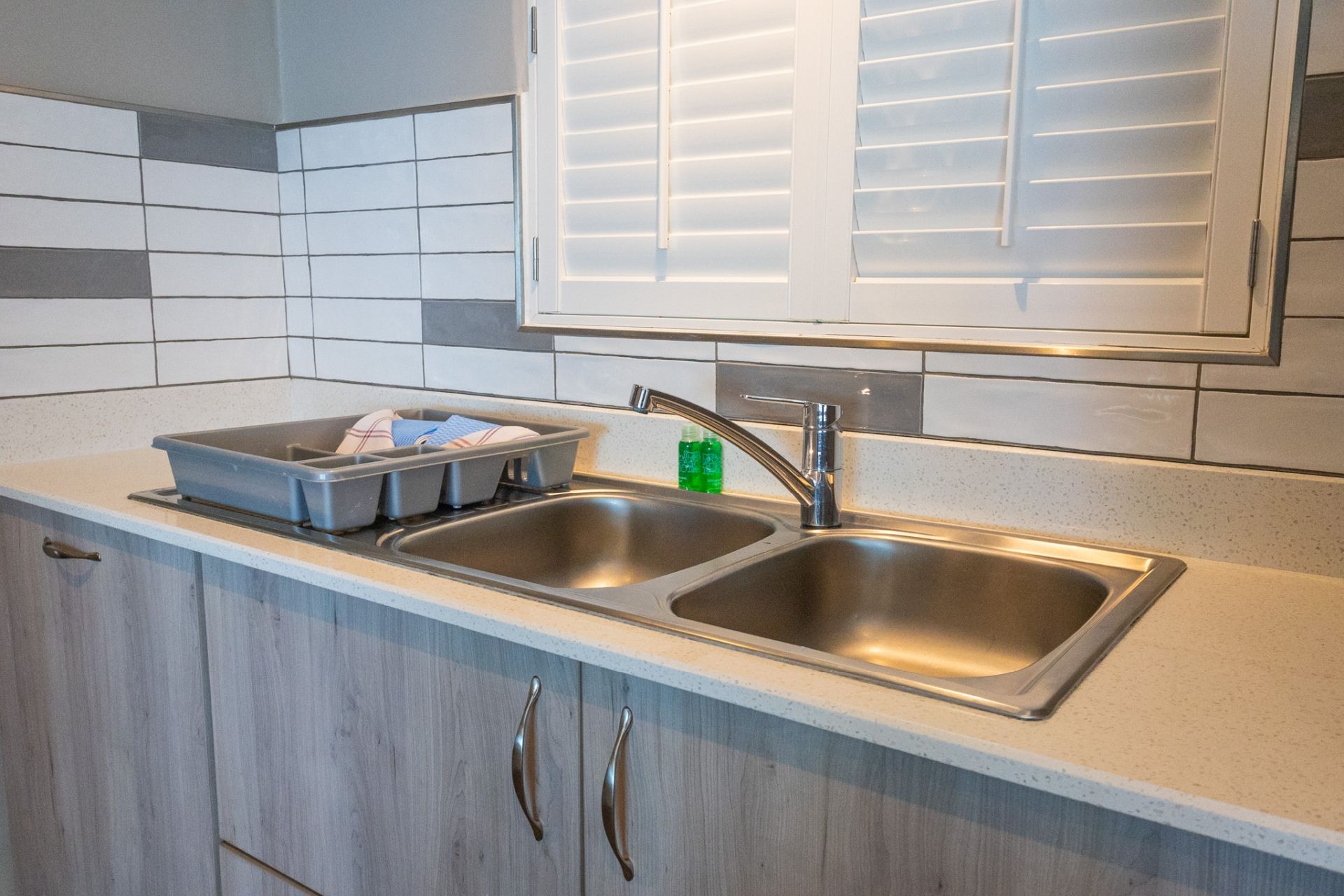 A kitchen with two stainless steel sinks, a dish rack, and a window above the sink.