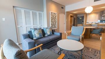 A modern living room with a sofa, chairs, a small table, and a patterned rug.