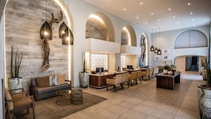 A spacious lobby with a modern design, featuring a reception desk, seating area, and decorative lighting. - Cabana Beach by First Private Stays (uMhlanga)