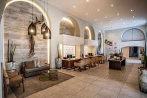 Um hall espaçoso com design moderno, que inclui um balcão de recepção, área de estar e iluminação decorativa.