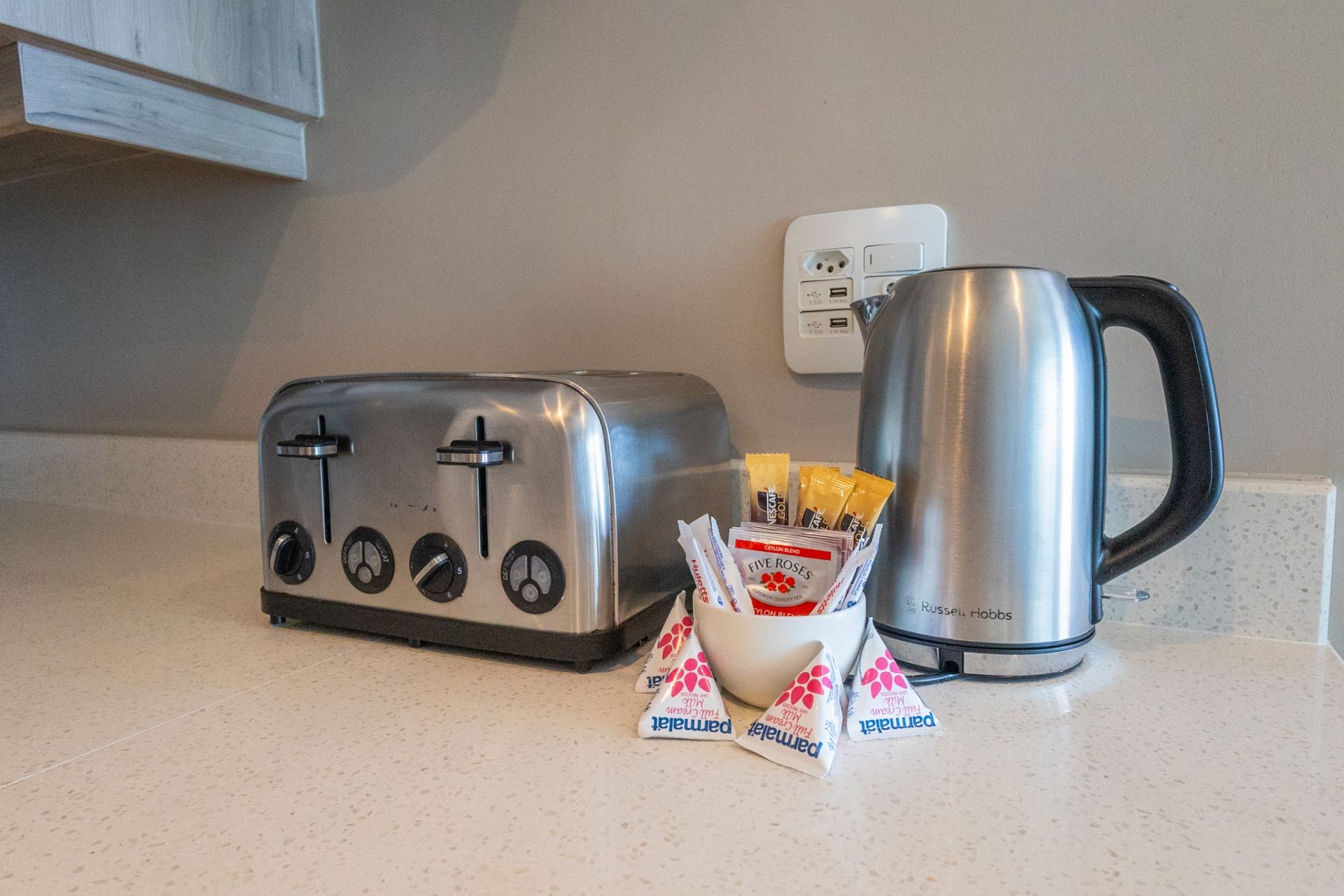 Una encimera de cocina con un tostador, una tetera y sobres de té.