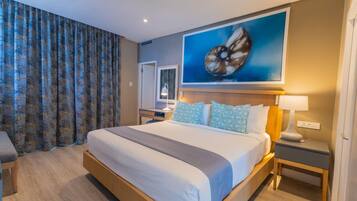 A hotel room with a large bed, a nightstand, a desk, and a painting on the wall.