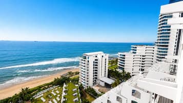 A beachfront hotel with multiple white buildings, a pool, and a view of the ocean.