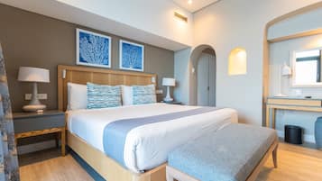 Habitació d'hotel amb un llit gran, dues taules de nit, una panxa, un mirall i dues làmpades penjades a la paret.