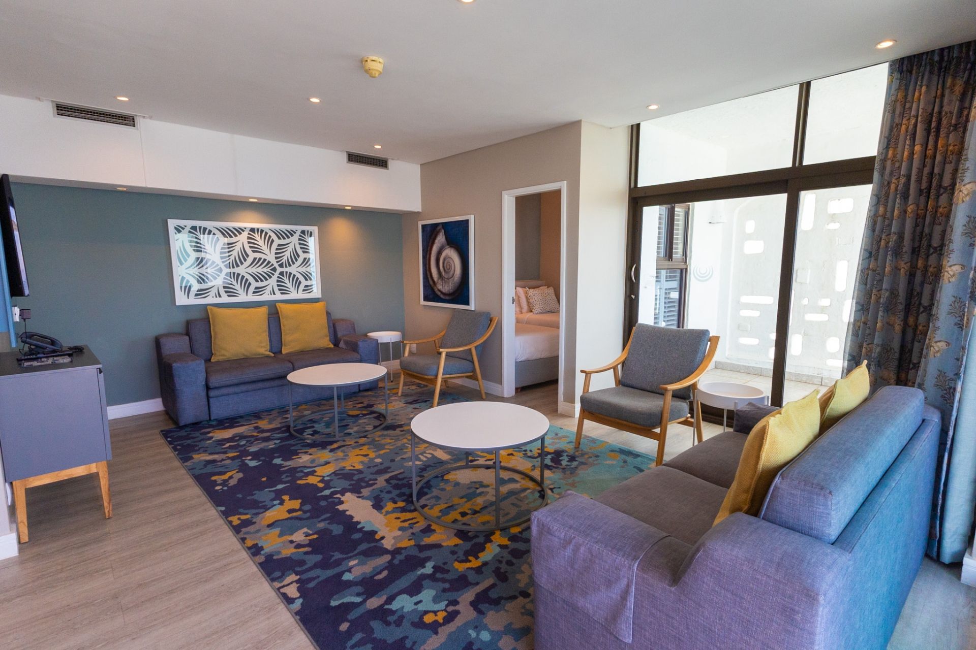 A modern living room with a sofa, armchairs, a coffee table, and a patterned rug.