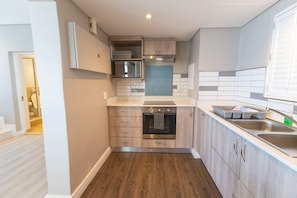 A compact kitchen with a microwave, oven, and sink.