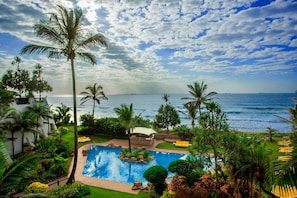 A pool area with a view of the ocean, surrounded by palm trees and a white building. - Cabana Beach by First Private Stays (uMhlanga)