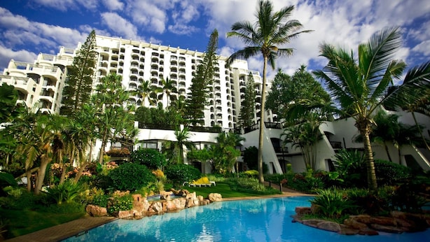 A hotel with a swimming pool surrounded by lush greenery and palm trees. - Cabana Beach by First Private Stays (uMhlanga)