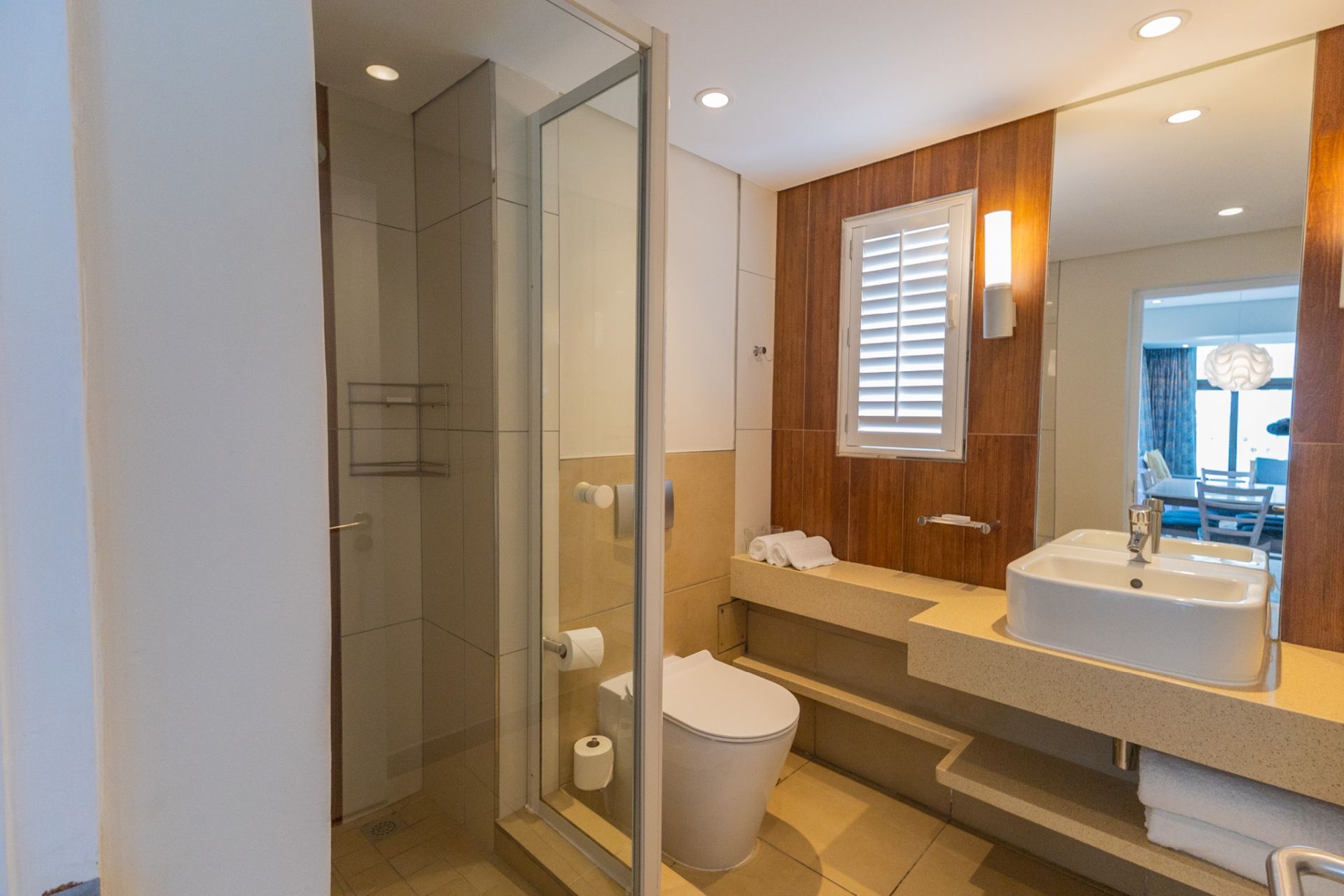 A modern bathroom with a glass shower enclosure, a toilet, a sink, and a vanity with a mirror.