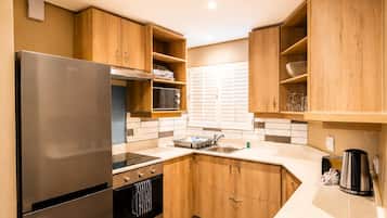 A compact kitchen with a stainless steel refrigerator, a built-in oven, and a microwave.