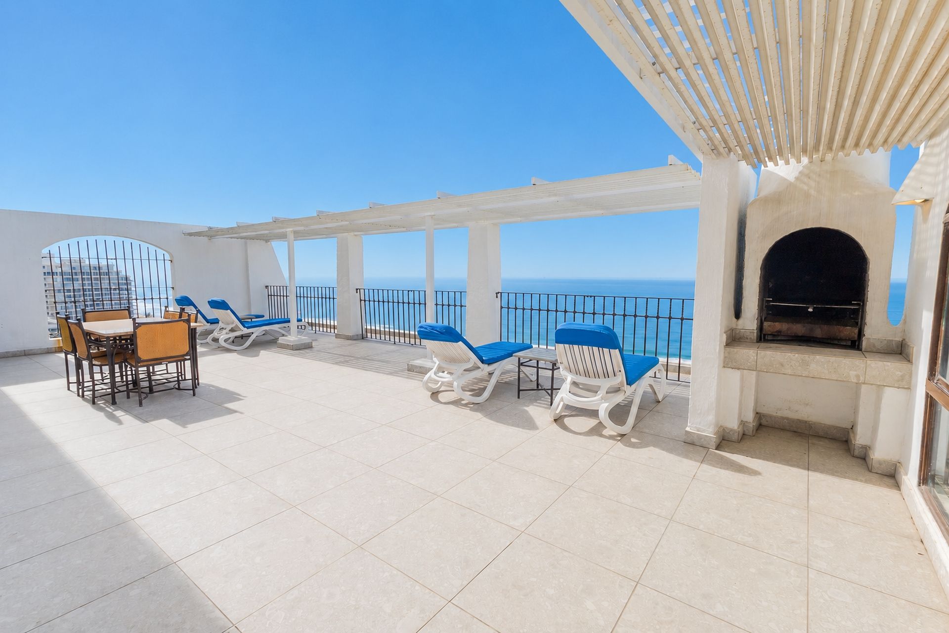A rooftop terrace with a dining set, lounge chairs, and a fireplace.