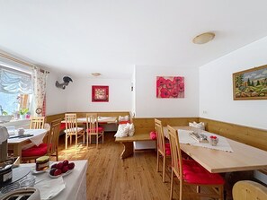 A dining area with wooden tables and chairs, a bench, and artwork on the walls.
