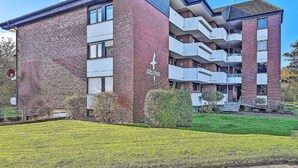 Ein modernes, mehrgeschossiges Gebäude mit Ziegelaußenwand, Balkonen und einer flachen Dachfläche.
