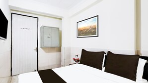 Ein Hotelzimmer mit einem Bett, einer Tür, einem Schrank und einem gerahmten Bild an der Wand.