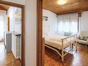 Ein Schlafzimmer mit einem Bett, einem Nachttisch, einem Heizkörper und einem Fenster mit Vorhängen.