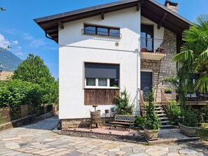 Ein zweigeschossiges Gebäude mit einer steinernen Fassade, einem Balkon und einer Steintreppe, die zu der oberen Etage führt.