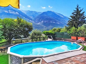 Ein Schwimmbad mit Blick auf eine Berglandschaft, umgeben von Grünflächen und einer Terrassenanlage.
