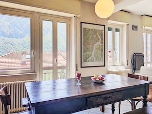 Ein Essbereich mit einem Holztisch, Stühlen, einer Obstschale und einer gerahmten Karte an der Wand.