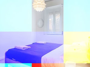 Ein Zimmer mit einem Bett, einem Fenster und einem Wandspiegel.