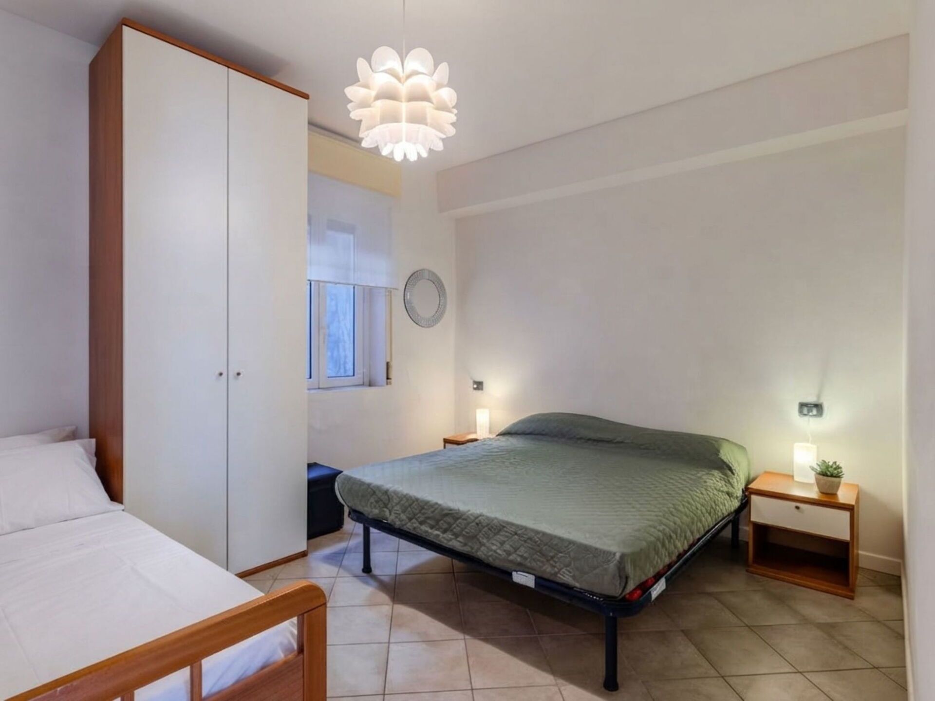 Un dormitorio con cama, mesitas de noche, armario e iluminación colgante.