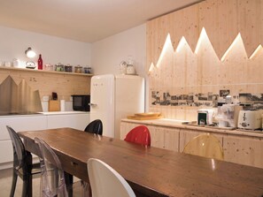 Une cuisine moderne dotée d’un plan de travail en bois, d’un réfrigérateur et d’un coin repas avec des chaises.