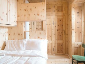 L’intérieur d’une cabane en bois, avec un lit, une chaise et une porte.