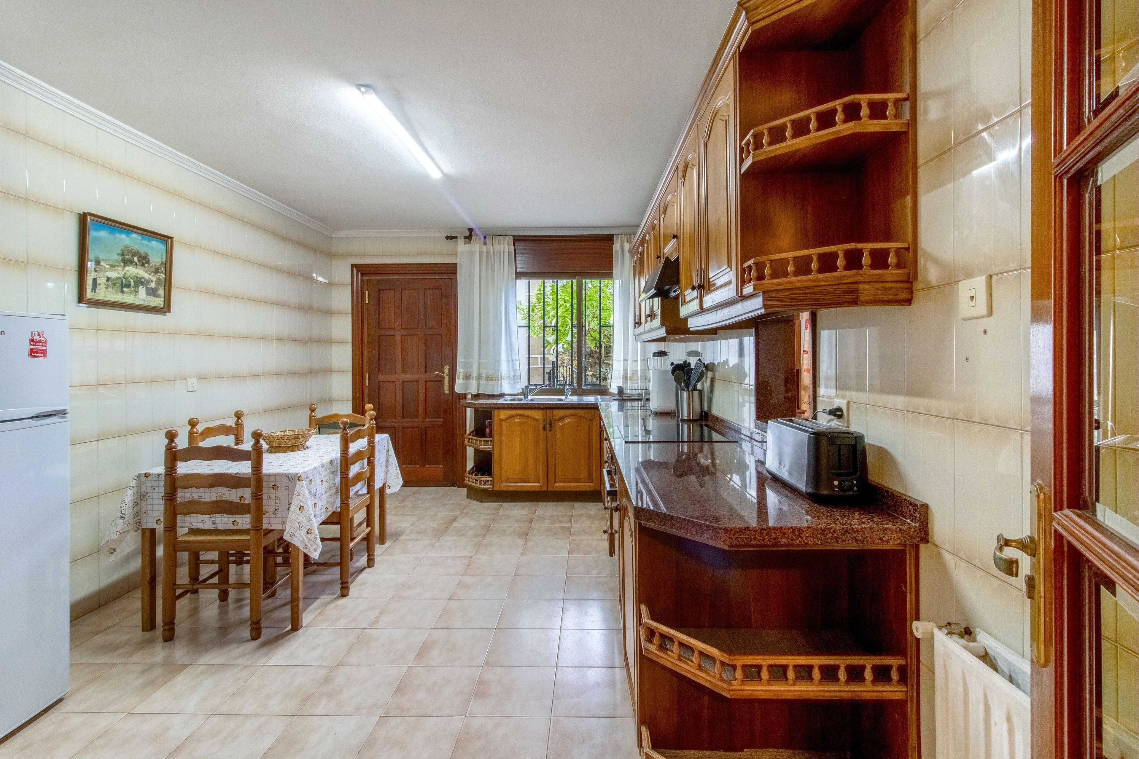 Eine Küche mit Holzausstattung, einem Esstisch mit Stühlen und einem Kühlschrank.