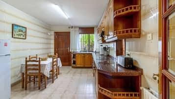 Eine Küche mit Holzausstattung, einem Esstisch mit Stühlen und einem Kühlschrank.