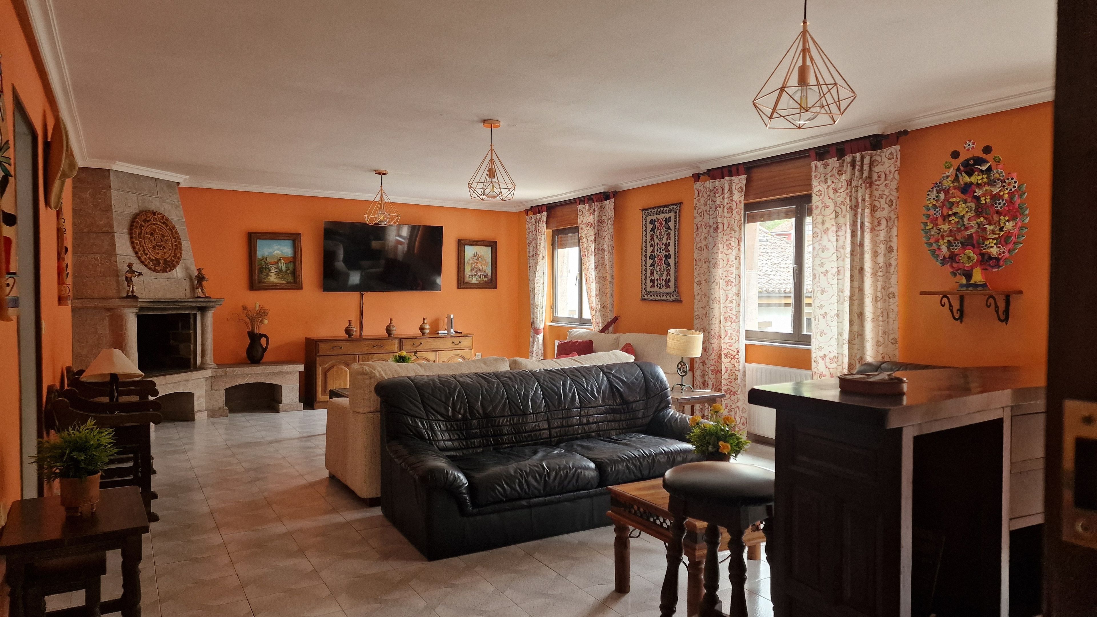 Uma sala de estar com sofá de couro preto, televisão e lareira.