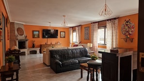 Una sala de estar con un sofá de cuero negro, un televisor y una chimenea.