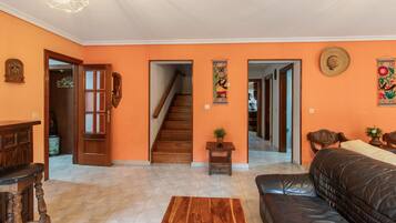 Una sala de estar con piso de madera, un sofá de cuero negro, una mesa de centro de madera y una escalera que conduce a otra habitación.