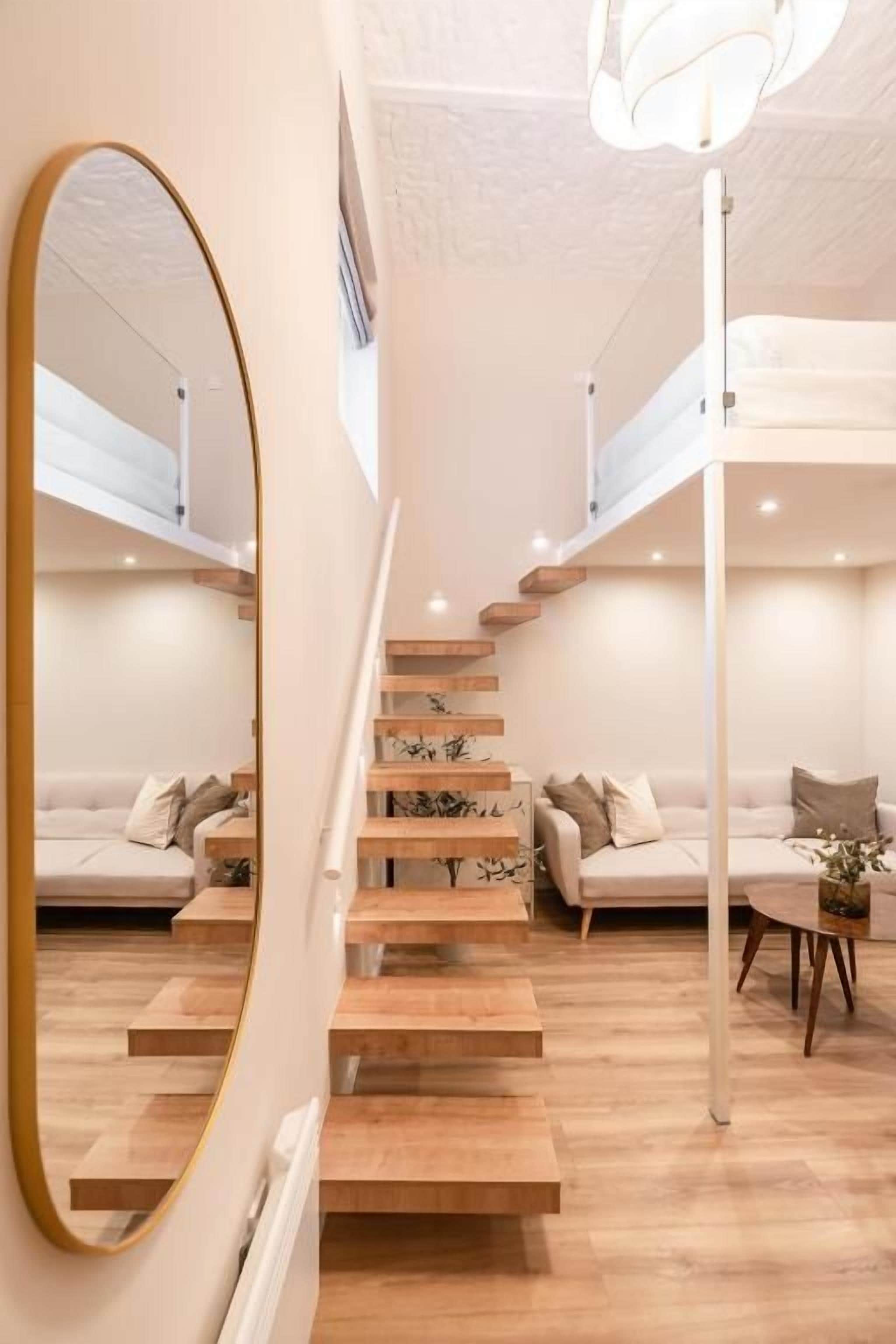 A modern interior with a staircase, a sofa set, and a dining table.