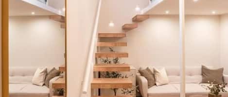 A modern interior with a staircase, a sofa set, and a dining table.