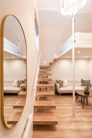 A modern interior with a staircase, a sofa set, and a dining table.