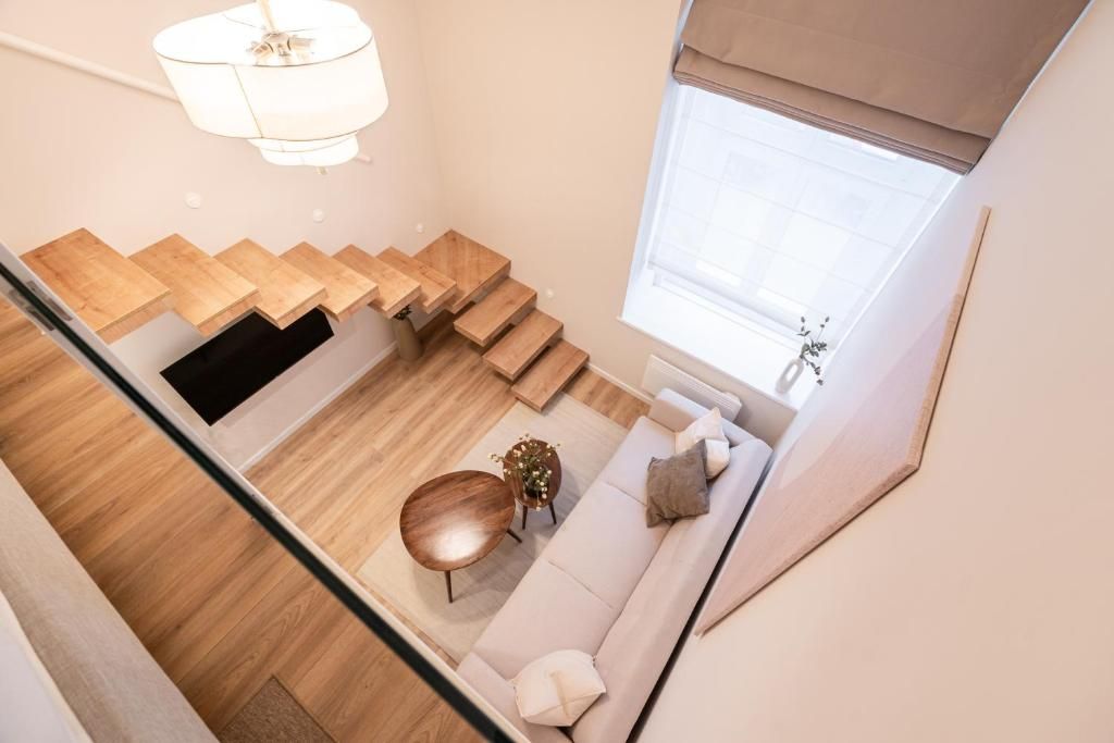 A modern interior with a staircase leading to a living area, a sofa, and a round wooden table.